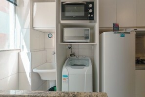 A compact kitchen with a microwave, a water dispenser, and a refrigerator. - Great Value Apartment in Zona 7 - GPAL207 (Maringá)