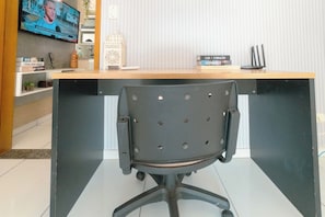 A modern office desk with a black office chair, a flat-screen TV mounted on the wall, and a few books on the shelf. - Great Value Apartment in Zona 7 - GPAL207 (Maringá)