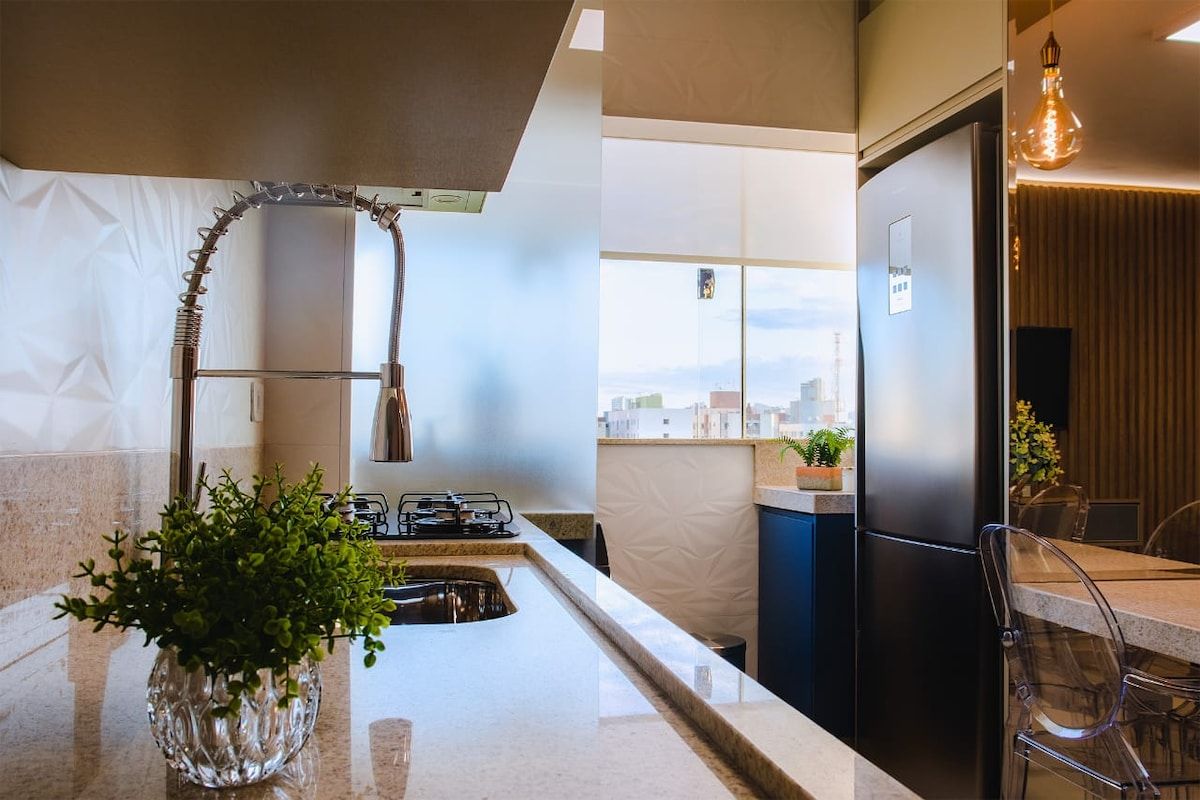Una cocina moderna con estufa a gas integrada, refrigerador de acero inoxidable y ventana con vista a la ciudad.