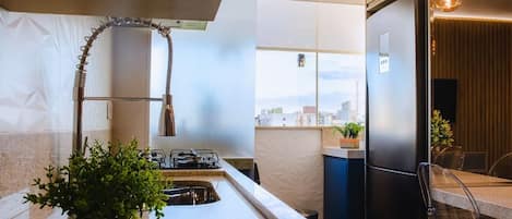Una cocina moderna con estufa a gas integrada, refrigerador de acero inoxidable y ventana con vista a la ciudad.