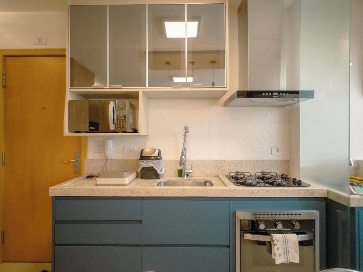 Una cocina compacta con lavamanos, estufa y armarios.