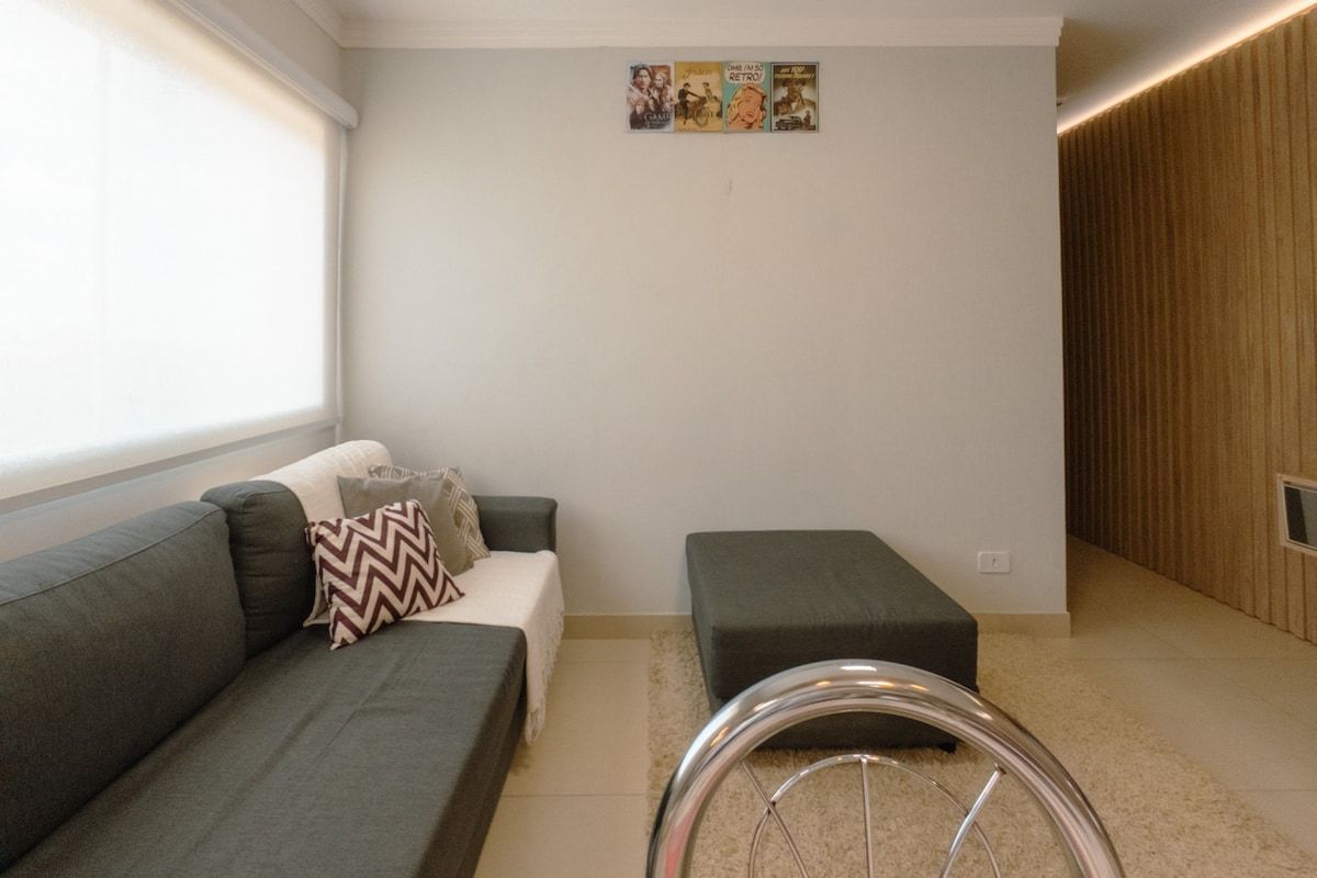 Una sala de estar moderna con un sofá gris, un otoman pequeño y una bicicleta al frente.