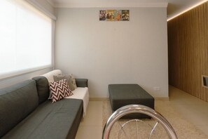 A modern living room with a grey sofa, a small ottoman, and a bicycle in the foreground.