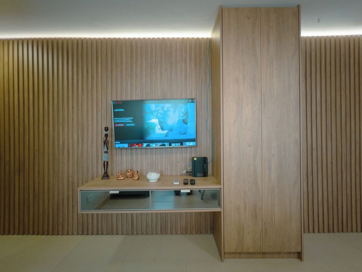 A modern entertainment unit with a flat-screen TV, a small speaker, and a decorative item.
