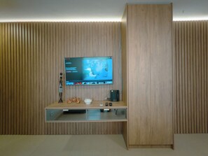 A modern entertainment unit with a flat-screen TV, a small speaker, and a decorative item.
