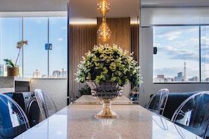 Ein moderner Konferenzraum mit Glastisch, Stühlen, einer dekorativen Vase mit Blumen und Blick auf die Stadt durch große Fenster.