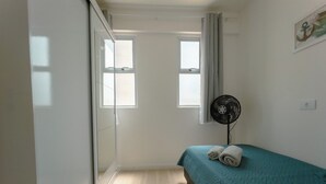 Et soveværelse med seng, ventilator og et vindue.