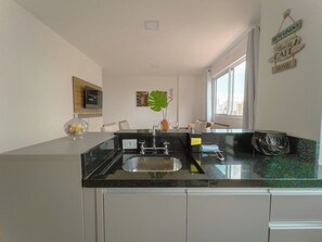 Una cocina moderna con encimera negra, pileta de acero inoxidable y ventana que permite entrada de luz natural.