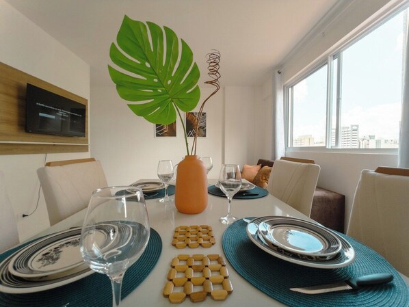 A dining area with a table set for four, including plates, cutlery, and glasses. - Two-Bedroom Apartment near the Cathedral - RC1102 (Maringá)