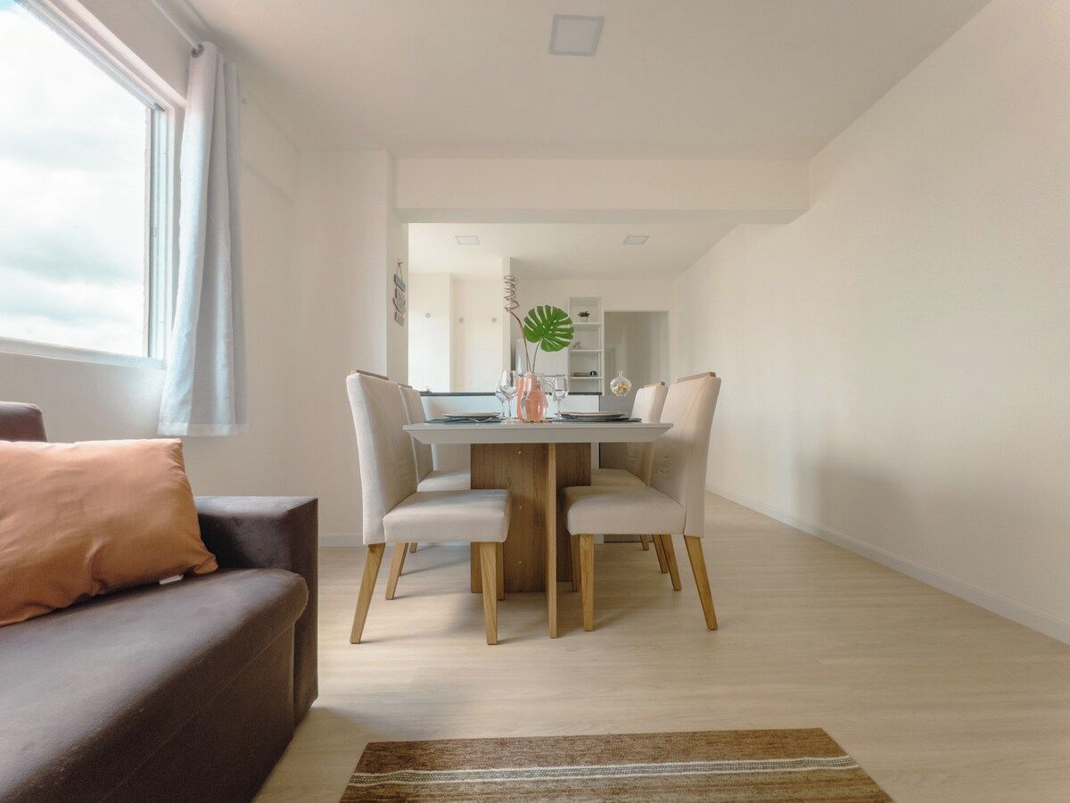 Ein modernes Wohnzimmer mit einer Couch, einem Esstisch mit Stühlen und einer Küche im Hintergrund.
