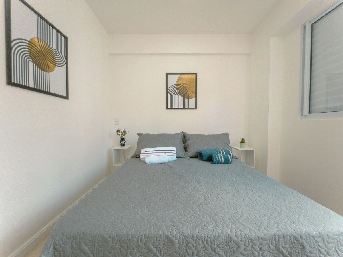 A bedroom with a large bed, two bedside tables, and two wall-mounted artworks.