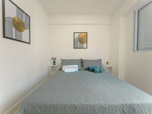 Un dormitorio con una cama grande, dos mesitas de noche y dos obras de arte colgadas en la pared.