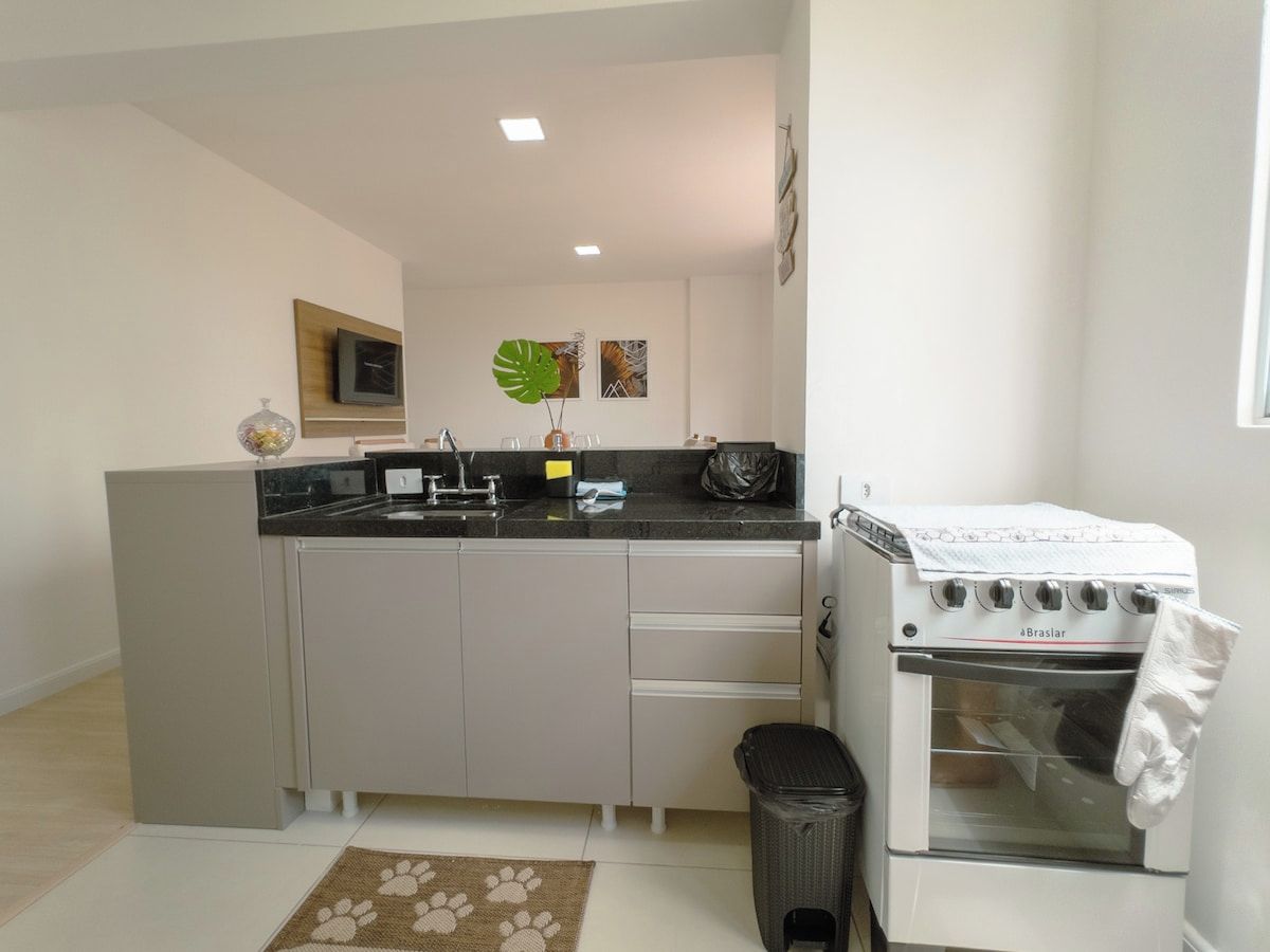 Cocina compacta con horno integrado, lavamanos y un cesto de basura.