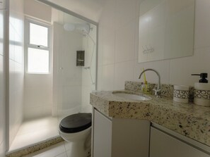A bathroom with a shower, toilet, sink, and mirror. - Two-Bedroom Apartment near the Cathedral - RC1102 (Maringá)