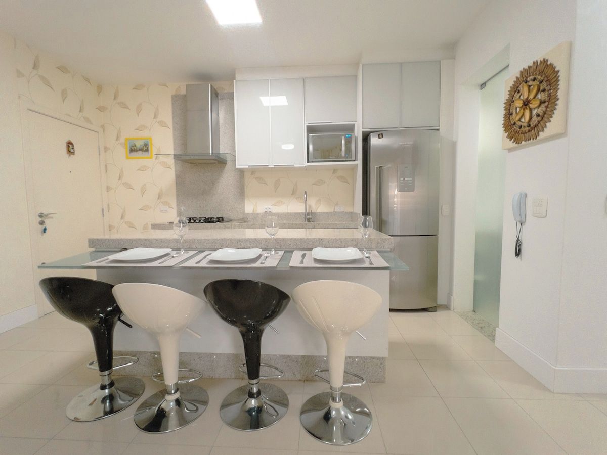 Una cocina moderna con una isla central, electrodomésticos de acero inoxidable y taburetes de bar.