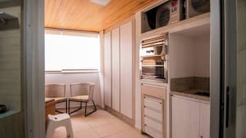 Cocina pequeña con armarios blancos, horno integrado y una encimera.