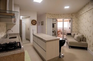 A modern kitchen with a central island, a dining area with a sofa, and a patterned wall.