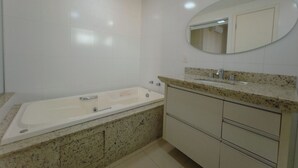 A bathroom with a bathtub, a sink, and a vanity with drawers. - Downtown Apartment next to Avenida Center - PL603 (Maringá)