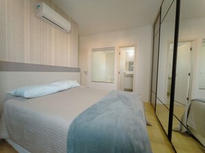 A bedroom with a bed, a wardrobe, and a mirror.