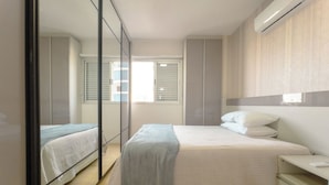A bedroom with a bed, bedside tables, a mirror, and a wardrobe. - Downtown Apartment next to Avenida Center - PL603 (Maringá)