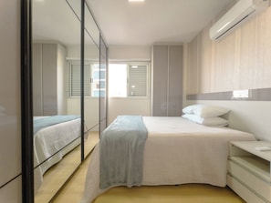 Ein Schlafzimmer mit Bett, Nachttischen, einem Spiegel und einem Kleiderschrank.
