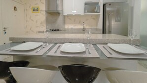 A modern kitchen with a central island, stainless steel appliances, and a dining area with a glass table. - Downtown Apartment next to Avenida Center - PL603 (Maringá)