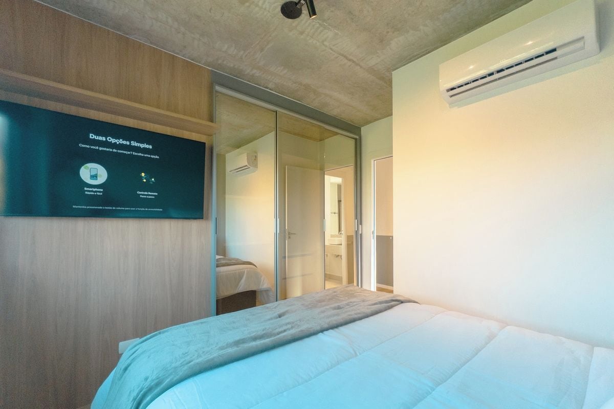 A bedroom with a bed, a wall-mounted air conditioner, and a sliding door closet.