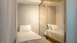 A small, modern bedroom with two beds, a glass partition, and a neutral color scheme. - Comfort and Style in Zona 7 for 5 Guests - BEDEO601 (Maringá)