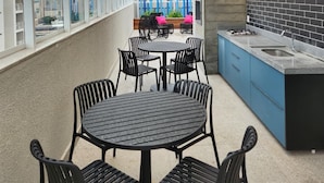 An outdoor patio with a round table and chairs, a built-in kitchen area, and a view of the cityscape. - Comfort and Style in Zona 7 for 5 Guests - BEDEO601 (Maringá)