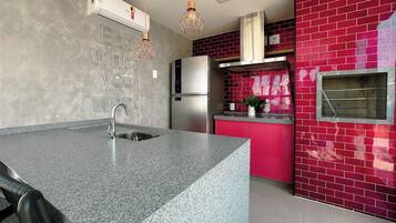 Cozinha com bancada de granito, eletrodomésticos de aço inoxidável e backsplash com azulejos vermelhos.