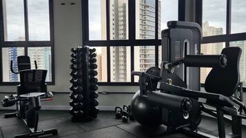 Ein Fitnessstudio mit Trainingsgeräten, großen Fenstern und Blick auf Gebäude.