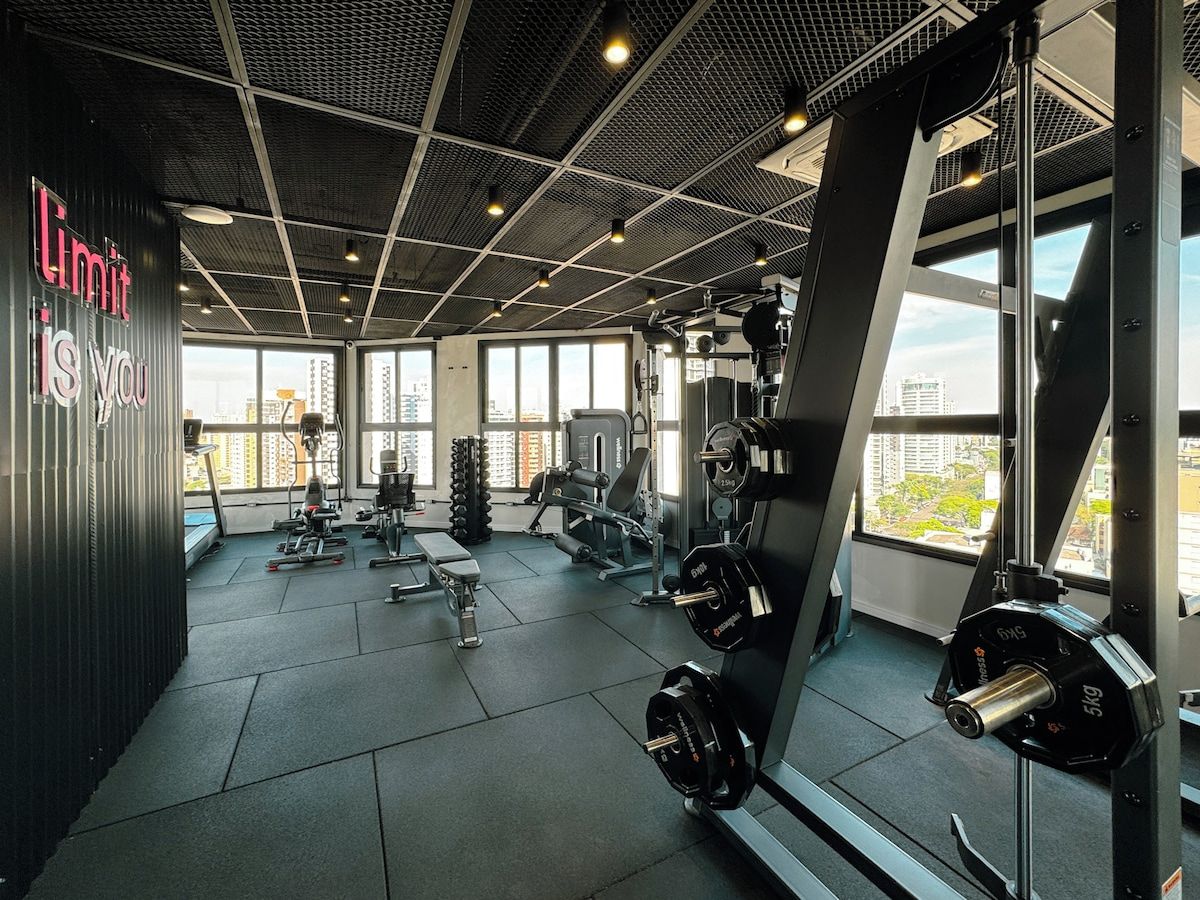 Ein Fitnessraum mit Gewichthebersportgeräten, Bänken und einem großen Spiegel, der den Raum widergibt.