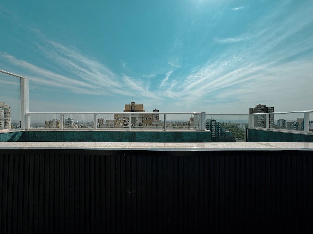 Eine Dachterrasse mit blauem Himmel, mit Blick auf eine Stadtlandschaft mit Gebäuden.