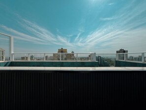 A rooftop terrace with a clear sky, overlooking a cityscape with buildings. - Modern Apartment in New Building - BEDEO505 (Maringá)