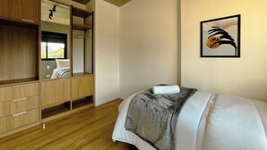 A bedroom with a bed, wooden wardrobe, and a framed picture on the wall. - Modern Apartment in New Building - BEDEO505 (Maringá)