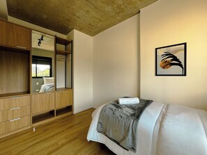 Ein Schlafzimmer mit einem Bett, einem Holzschrank und einem gerahmten Bild an der Wand.
