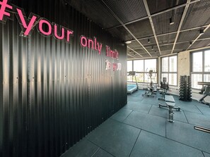 Een sportschool met een motiverende muur en diverse fitnessapparaten.