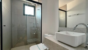 A modern bathroom with a glass-enclosed shower, a white sink, and a toilet. - Modern Apartment in New Building - BEDEO505 (Maringá)