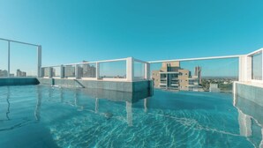 A rooftop infinity pool with clear blue water, surrounded by modern buildings and a clear sky. - Private Room with Pool and Gym - BEDEO302B (Maringá)