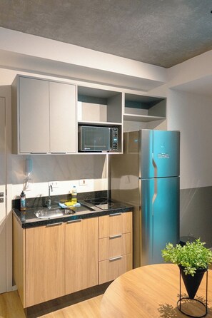 Une cuisine moderne équipée d’un four à micro-ondes, d’un réfrigérateur bleu, de meubles en bois, d’un évier et d’une plante en pot.