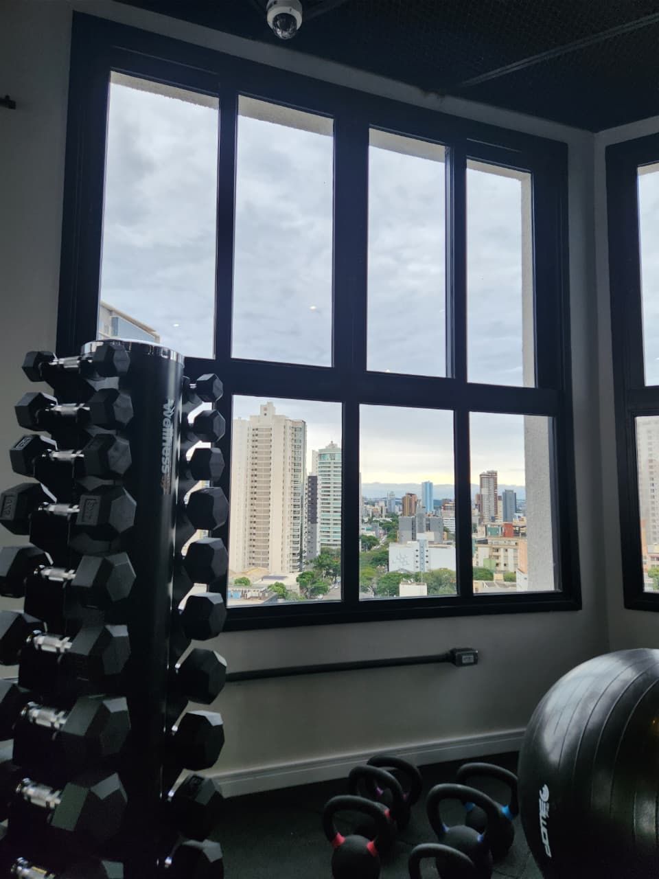 Un gimnasio con vistas a un paisaje urbano a través de amplios ventanales.