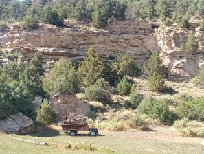 A vehicle parked in a natural setting with a rocky cliff and sparse vegetation.