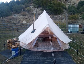 A tent set up in an outdoor area with a wooden structure nearby, a blue bucket, and a patterned mat on the ground. - Beautifull Chicosa Canyon 2 Glamping with kitchen, hot shower and pet friendly. (Trinidad)