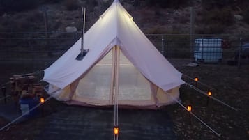 A tent with a peaked roof, surrounded by a fence, and a basketball hoop in the background.