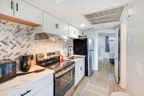A modern kitchen with white cabinets, a stainless steel stove, and a black refrigerator. - New Oceanview Suite Bluewater Villas with Pools (Myrtle Beach)