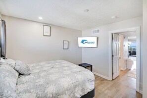 Un dormitorio con una cama, un televisor y una puerta que da a un balcón.