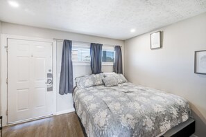 A bedroom with a bed, curtains, a door, and a window. - New Oceanview Suite Bluewater Villas with Pools (Myrtle Beach)