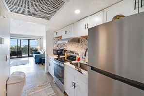 A modern kitchen with stainless steel appliances, white cabinetry, and a large refrigerator. - New Oceanview Suite Bluewater Villas with Pools (Myrtle Beach)