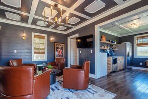 A modern living room with leather chairs, a dining area, and a kitchen with a built-in refrigerator.