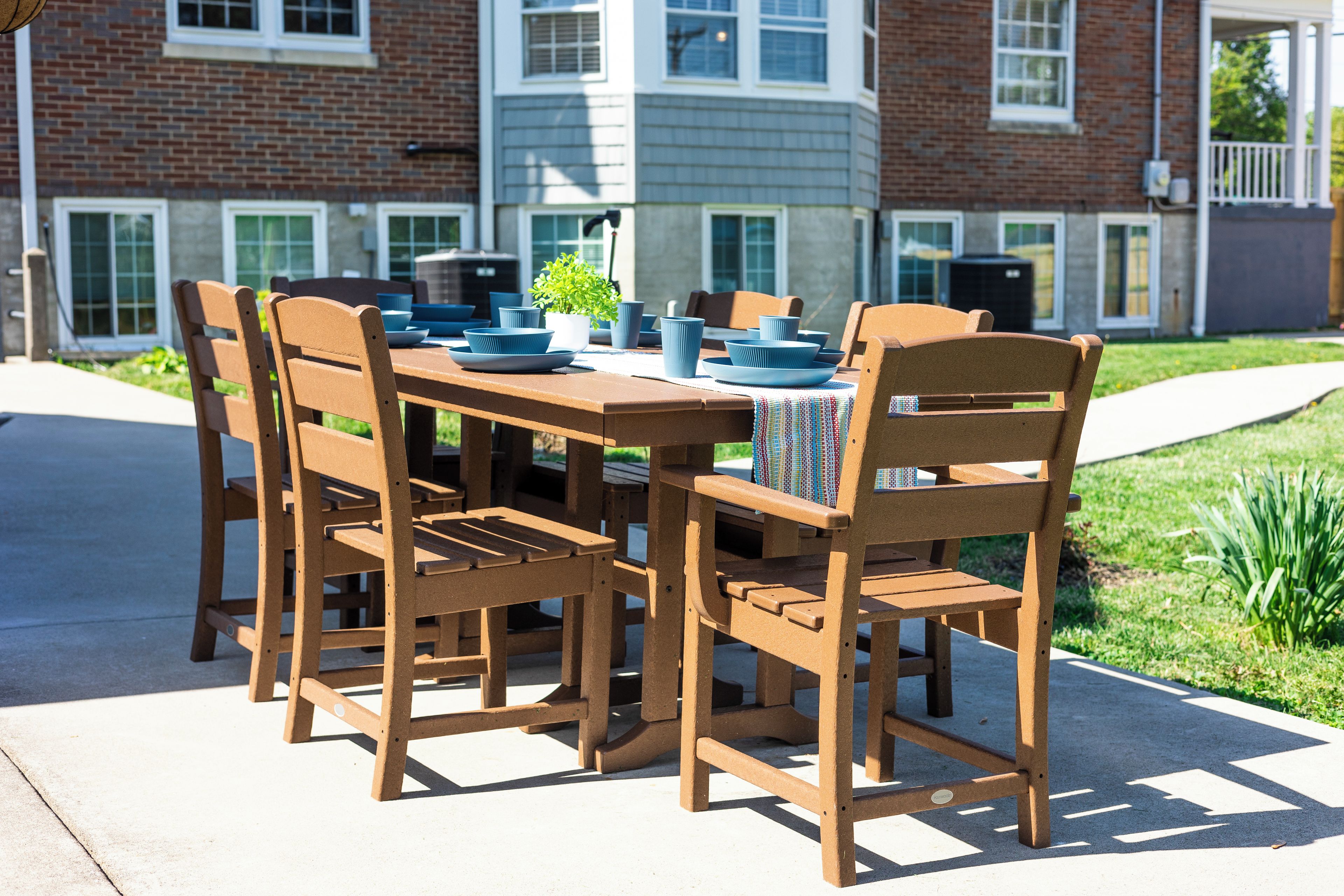 An outdoor dining area with a table set for four, surrounded by wooden chairs.